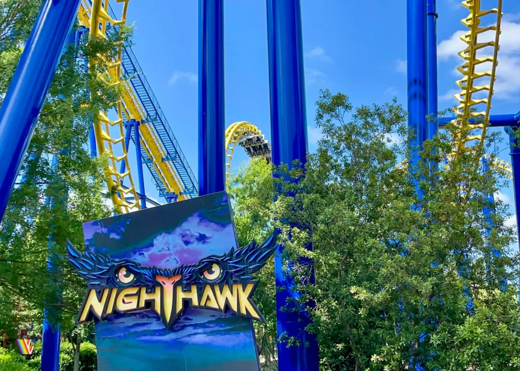 Entrance to Nighthawk roller coaster at Carowinds with train going through vertical loop behind it