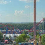 From the skyride, looking at Superman Ultimate Flight and Green Lantern roller coasters down boardwalk area at Six Flags Great Adventure. Parachute Drop and Slingshot are in foreground.