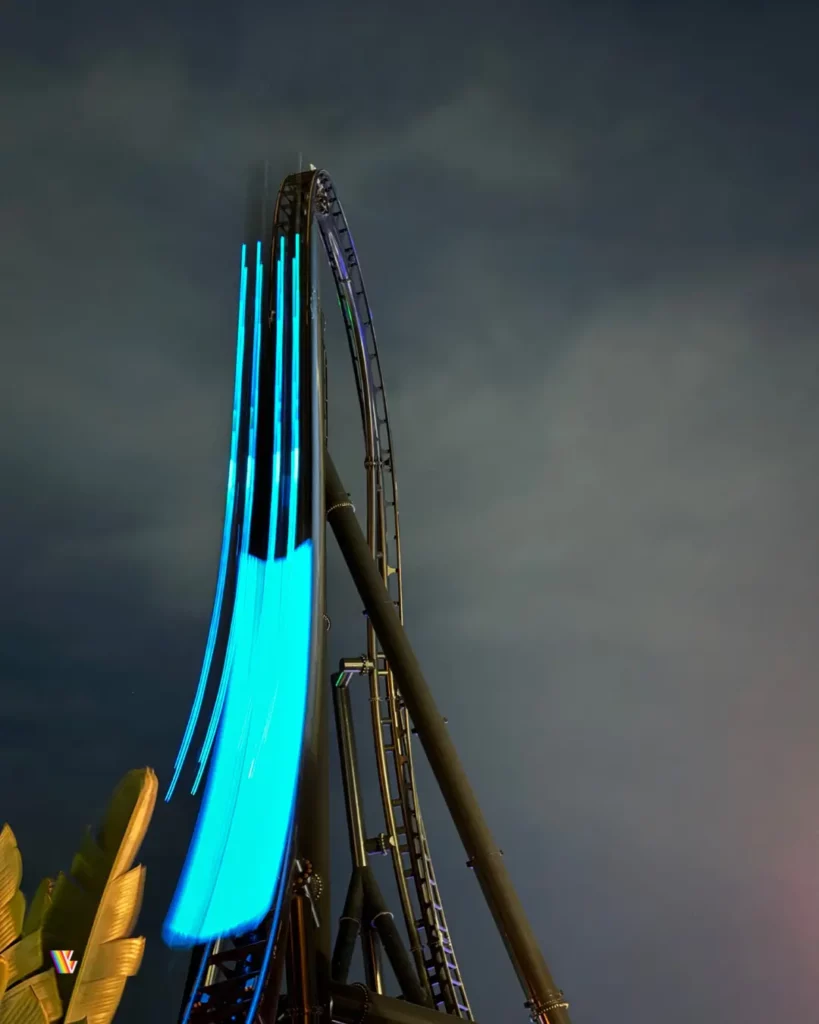 Jurassic World VelociCoaster, one of the fastest roller coasters in Florida, going down its top hat at night with lights from the train's long exposure