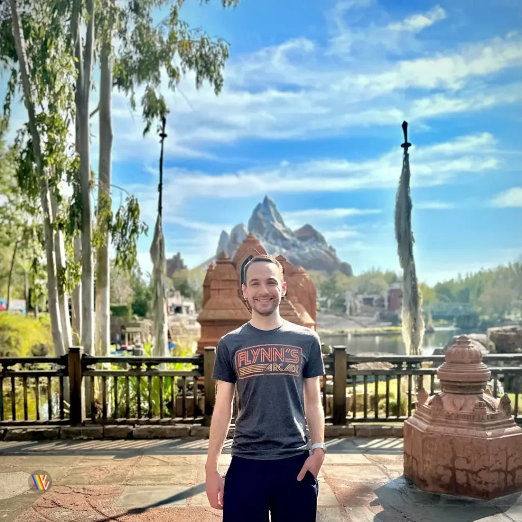 Christian McIlwain of Vertigo Views, a light skinned man, standing and smiling in front of Expedition Everest statue at Disney's Animal Kingdom at Walt Disney World