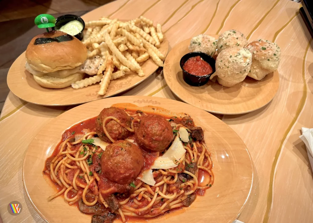 Food sitting on table in Toadstool's Cafe at Universal Studios Hollywood, including a chicken burger and fires, spicy spaghetti and meatballs, and garlic knots