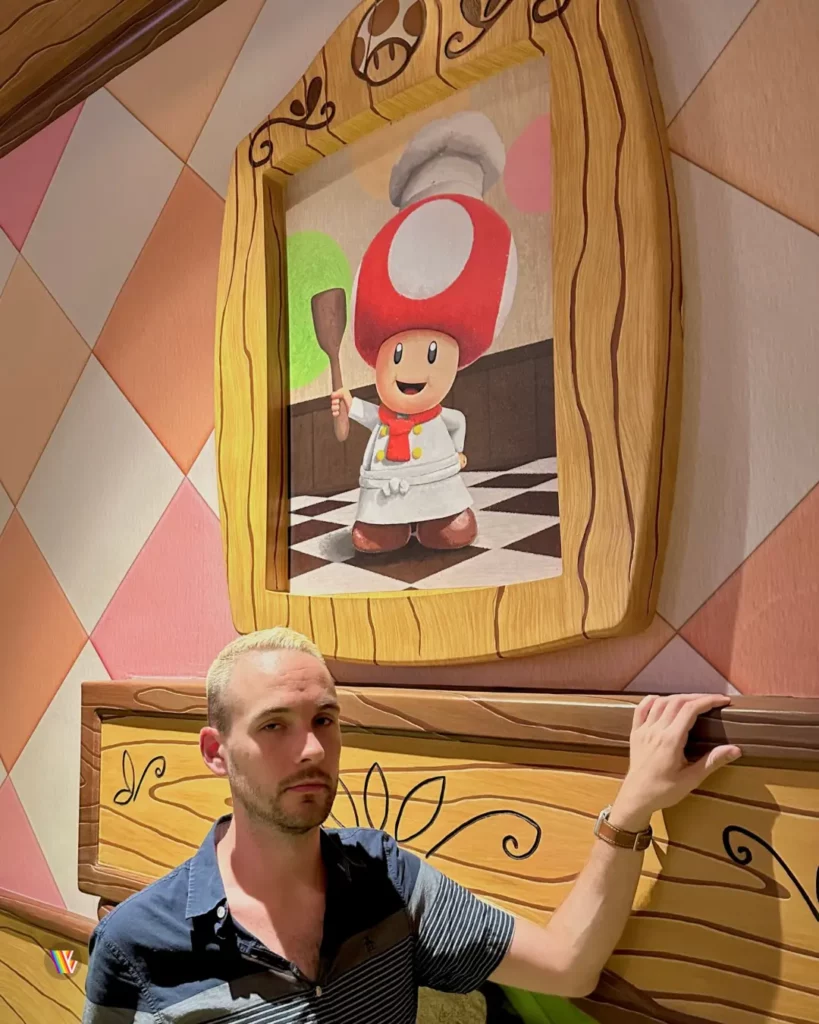 Christian McIlwain standing angrily next to fireplace with portrait of Toad above it in Toadstool's Cafe at Universal Studios Hollywood